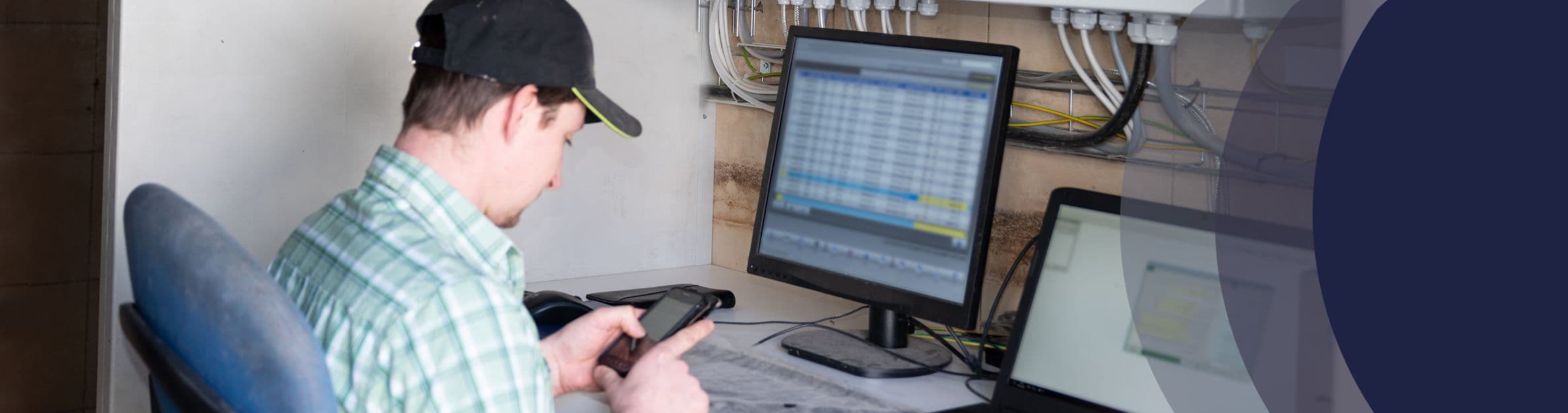 man looking at phone by computer