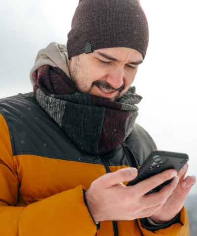 Man with winter gear looking at cell phone