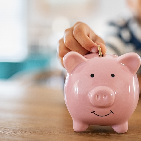 hand putting a coin into a piggy bank