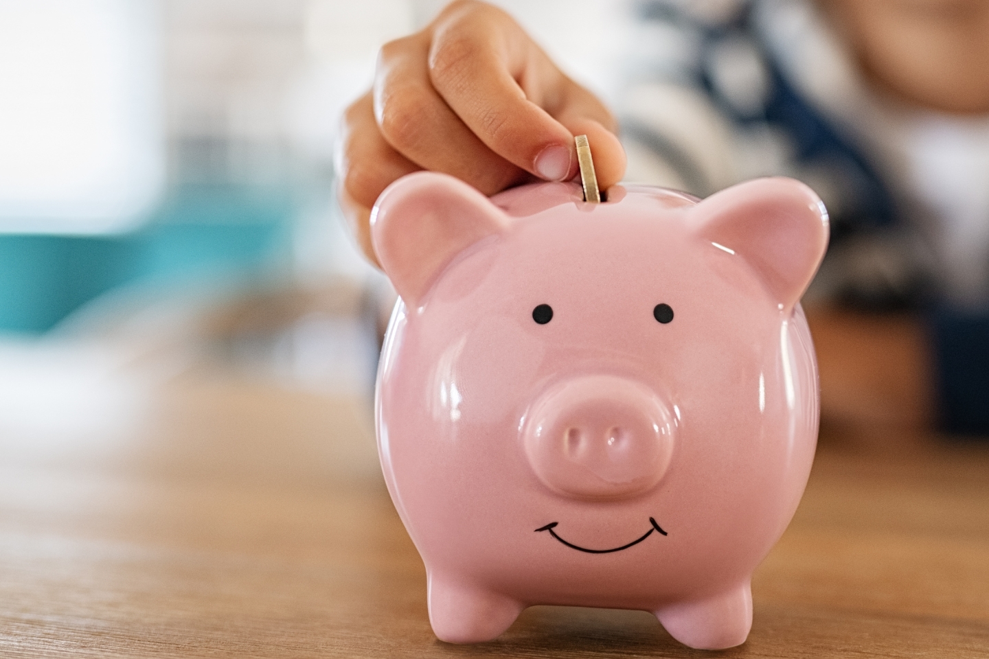 hand putting a coin into a piggy bank