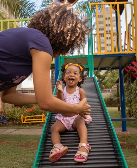 mom helped happy daughter down a slide