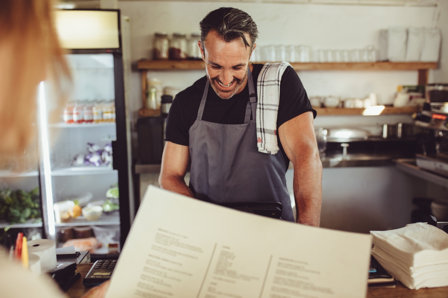 Male business owner looking down smiling at counter