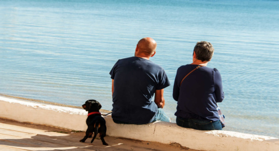 Couple and dog sitting by water