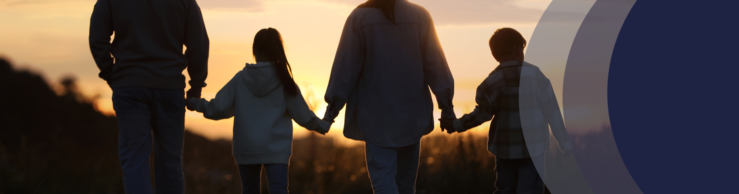 Dad, daughter, mom, son walking in a field at sunset
