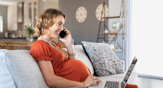 Pregnant woman looking at a laptop while on the phone